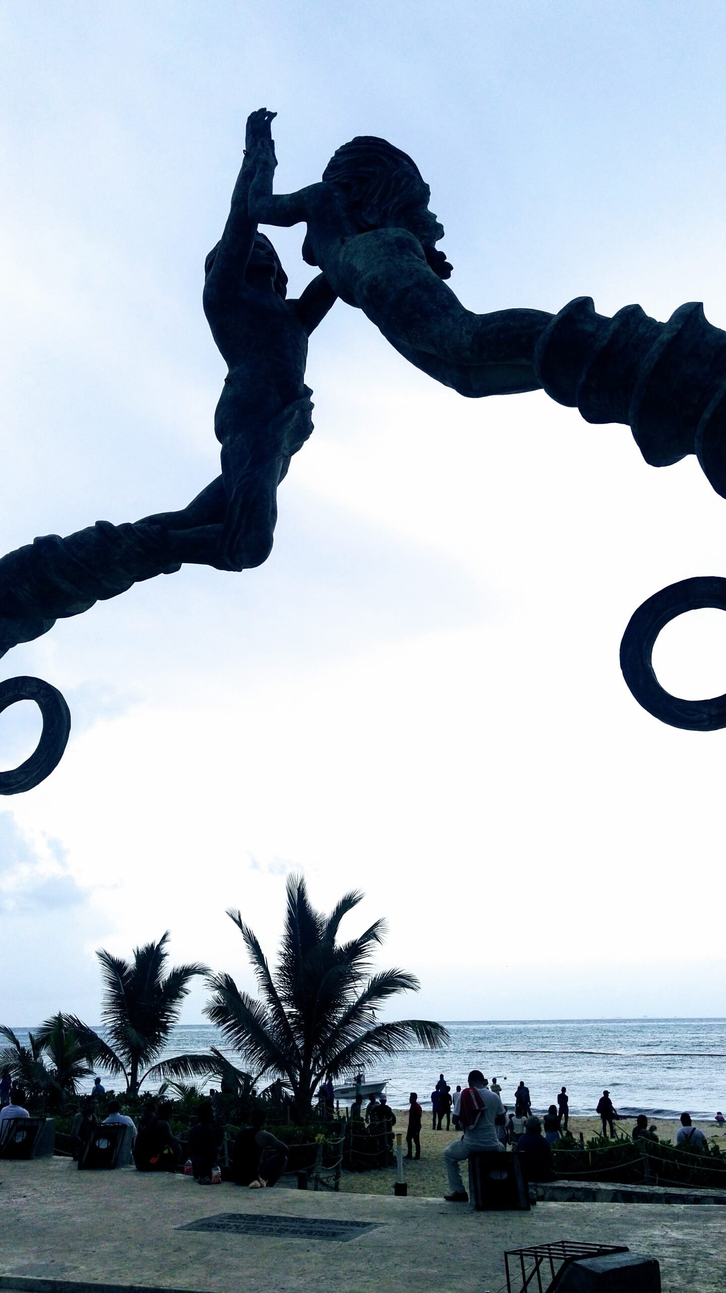 two mermaids making arch stature of metal over palm tree plaza